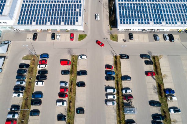 Shopping center with solar photovoltaic panels on the roofs and a parking lot with cars, aerial view.